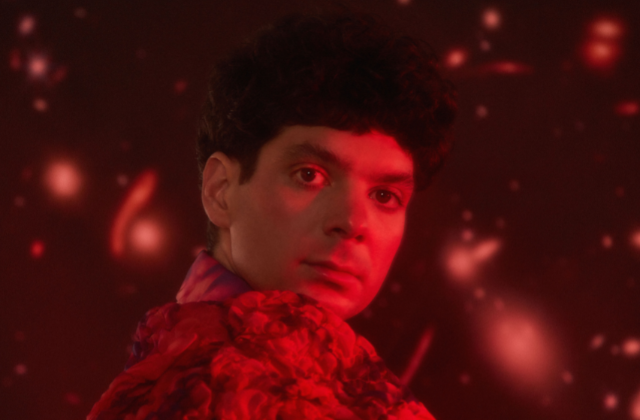 Imagem mostra homem com roupa florida iluminado por luz vermelha