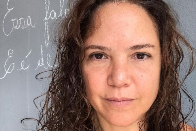 Tereza Seiblitz posa com semblante neutro diante de lousa. A foto está recortada apenas em seu rosto