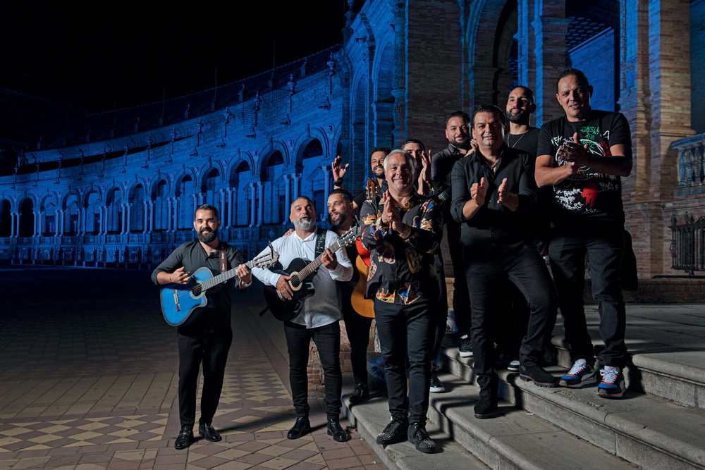 Imagem mostra grupo de pessoas com instrumentos, em escada, com construção azulada ao fundo