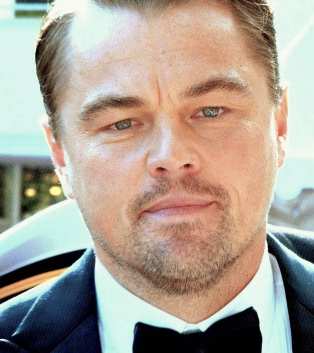 Foto com close no rosto de Leonardo DiCaprio usando terno em evento.