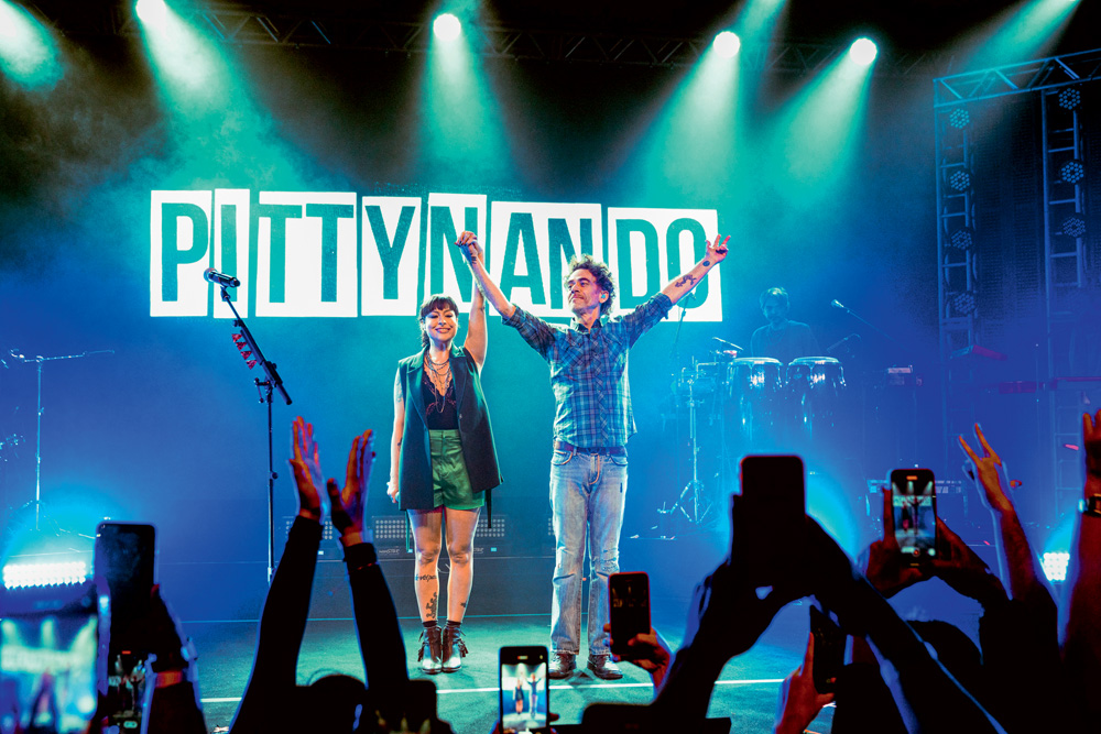 PittyNando – crédito Lucca Miranda 1.jpg Imagem mostra mulher e homem no palco, com os braços levantados