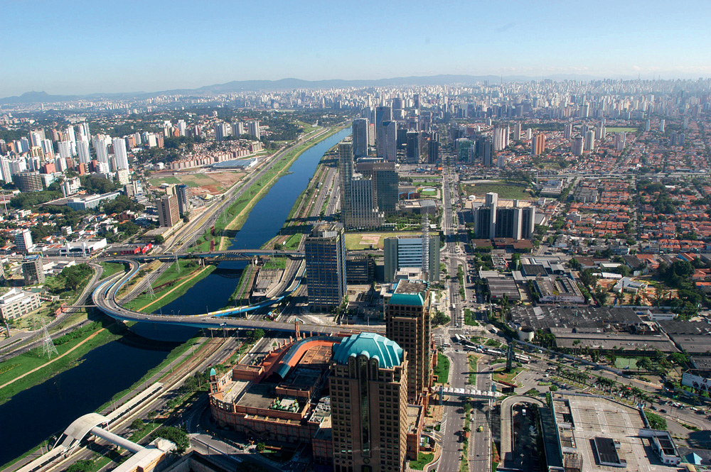 Imagem aérea mostra horizonte de bairros ao lado de rio