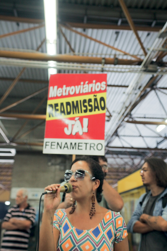 Camila fala ao microfone em ato pela readmissão (2018)