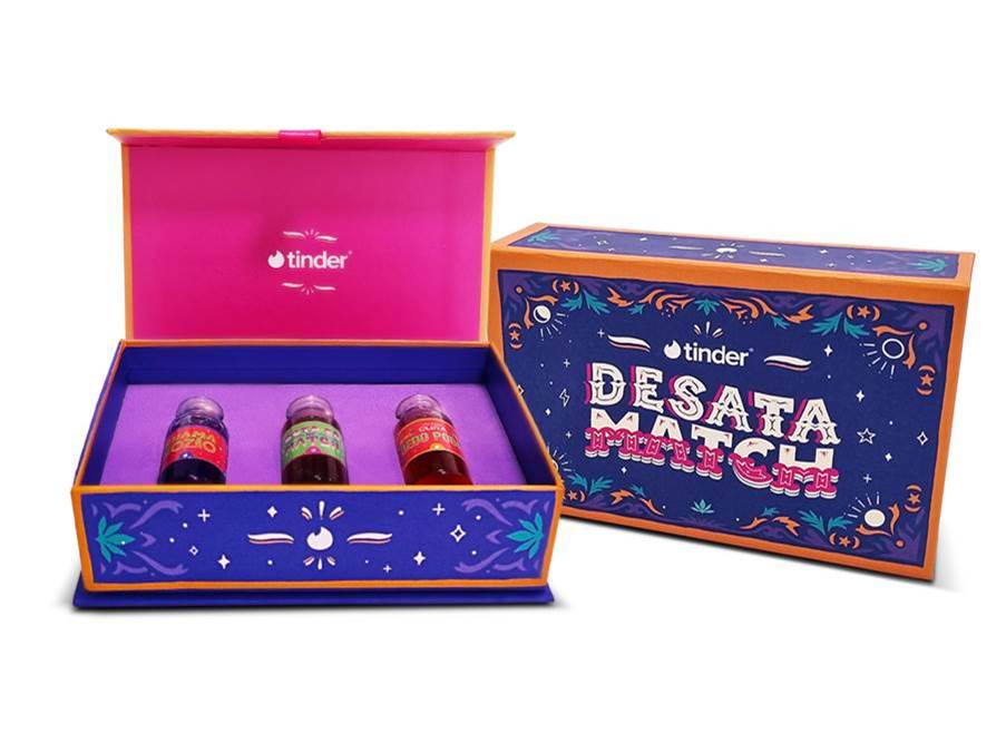 Caixa roxa e rosa com três vidros de essências. A foto exibe uma caixa aberta e outra fechada com os dizeres DESATA MATCH.