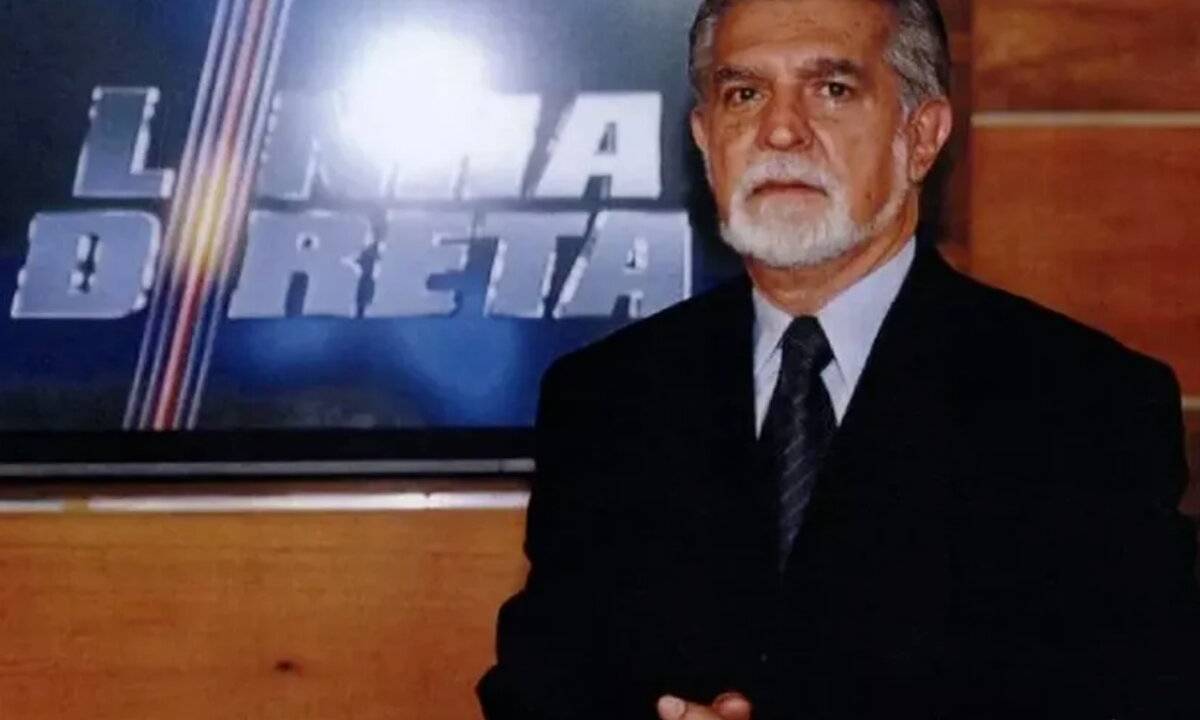 Domingos Meirelles posa diante de televisão com o logo do 'Linha Direta'