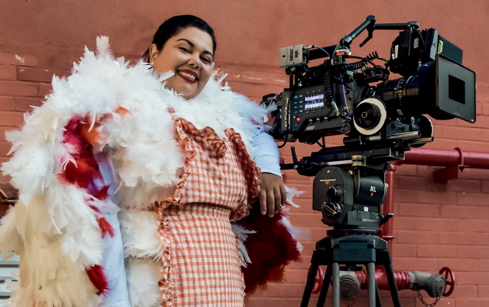 Imagem mostra mulher sorrindo ao lado de câmera de cinema