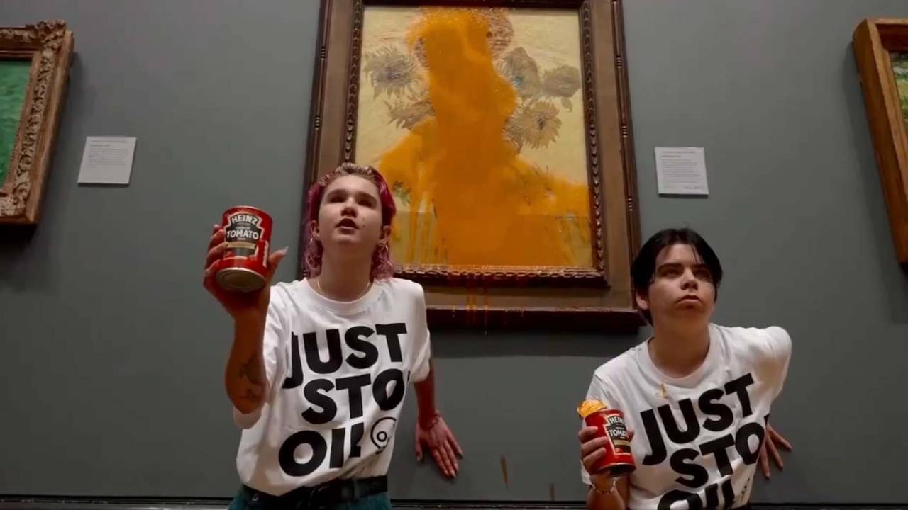 Ativistas posam segurando latas de sopa de tomate em frente do quadro de Van Gogh, sujo
