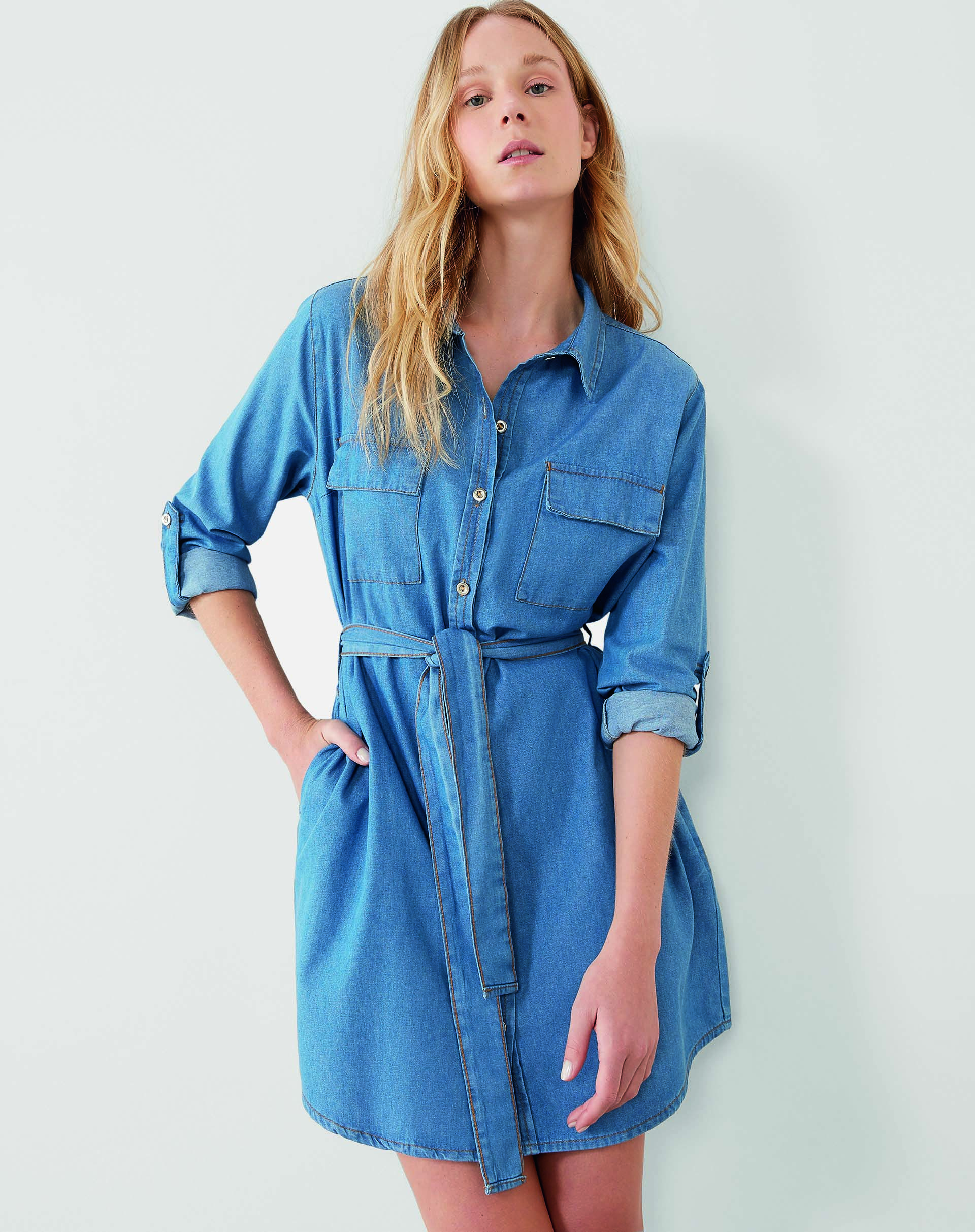 Modelo branca, magra e loira veste chemise jeans curta