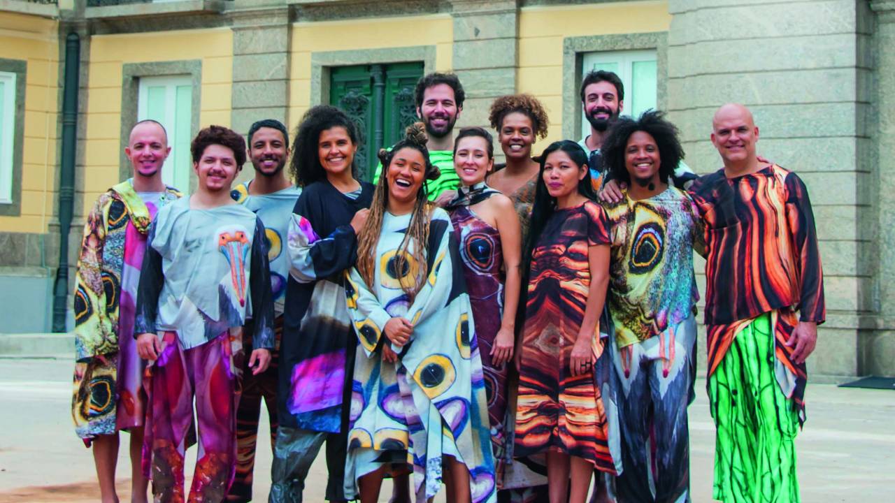 Companhia de teatro tem atores vestidos com longas túnicas coloridas e estampadas em frente ao Museu Nacional, no Rio de Janeiro
