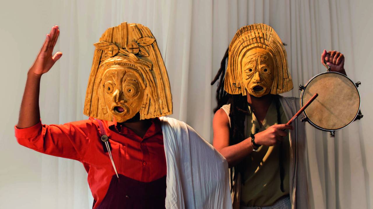 Dois atores negros com máscaras coloridas
