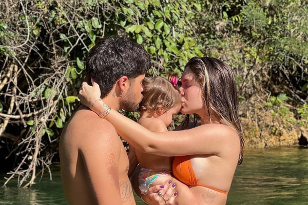 Zé Felipe e Virginia Fonseca beijam a primeira filha do casal, Maria Alice, enquanto estão na água.