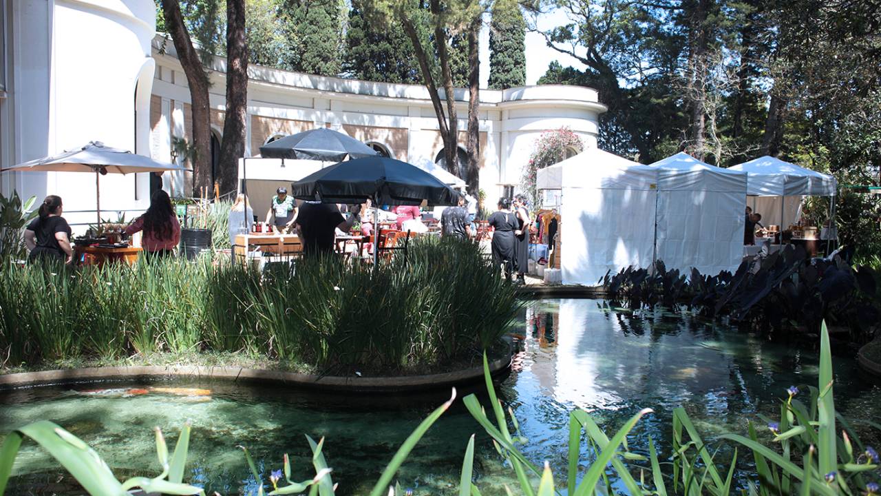 Foto de jardins da Casa Museu Ema Klabin com barracas verde e brancas do Bazar da Cidade.