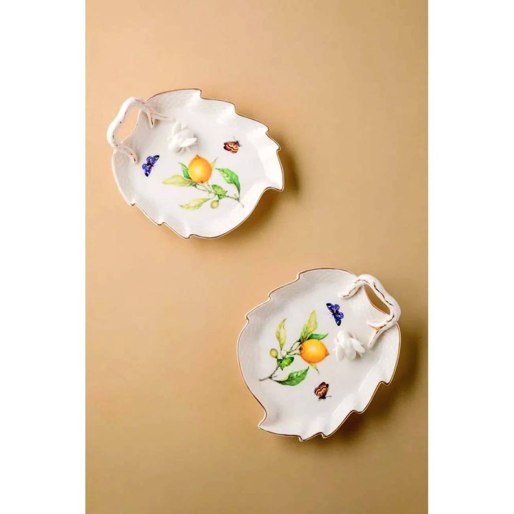 Duas petisqueiras de porcelana branca em formato de folha. Ambas têm a mesma estampa de um galho de laranja com borboletas ao redor