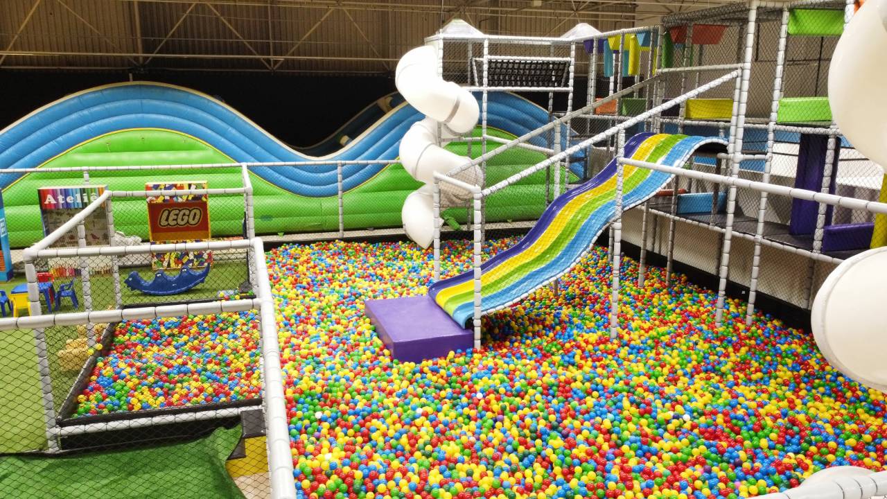 Parque indoor com piscina de bolinhas coloridas, escorregadores e infláveis visto de cima