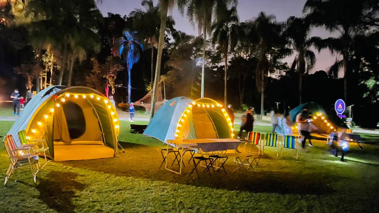 Barracas de acampamento envoltas em luzes amarelas no Parque Burle Marx. Está de noite