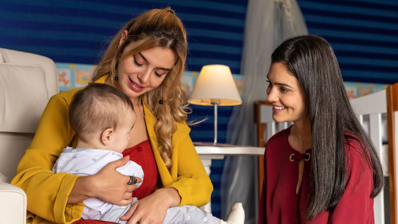 Duas mulheres sorriem, e uma está com um bebê no colo