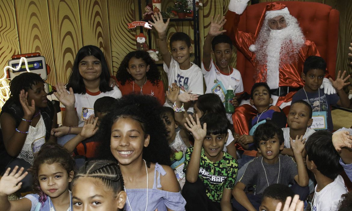 Foto de crianças comemorando, com Papai Noel ao fundo