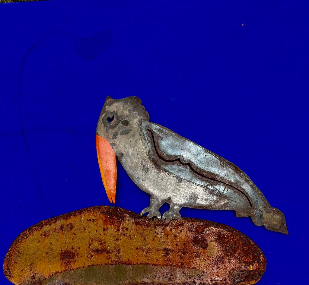 animofras Peça em metal enferrujado em formato de tucano. Seu bico é laranja