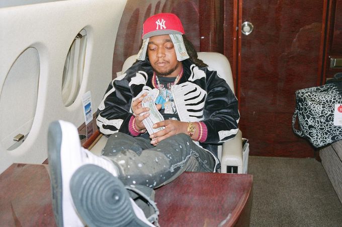 Foto de Rapper Takeoff sentado em jatinho particular, com os pés sobre a mesa