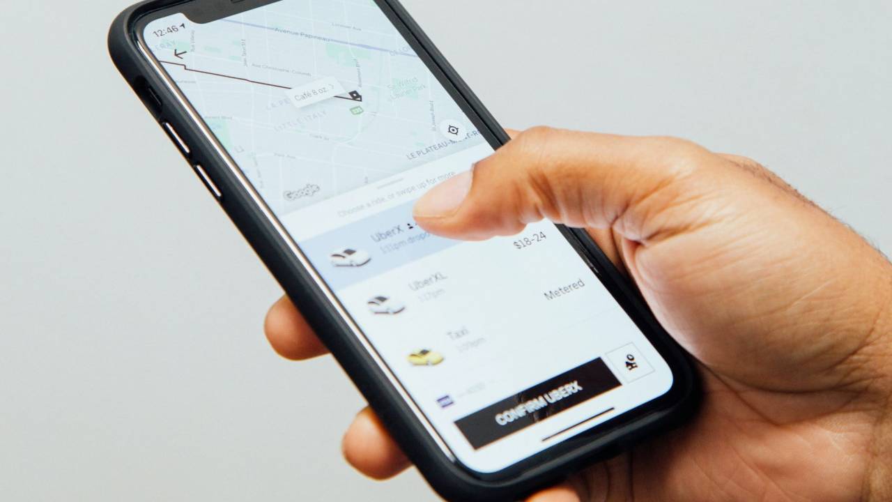 Foto de mão segurando celular com aplicativo do Uber aberto