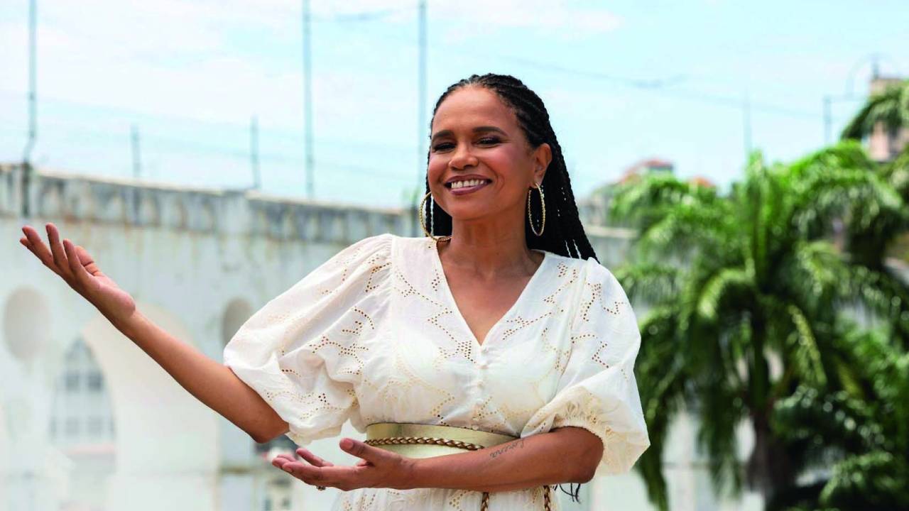 Imagem mostra mulher de vestido branco, sorrindo