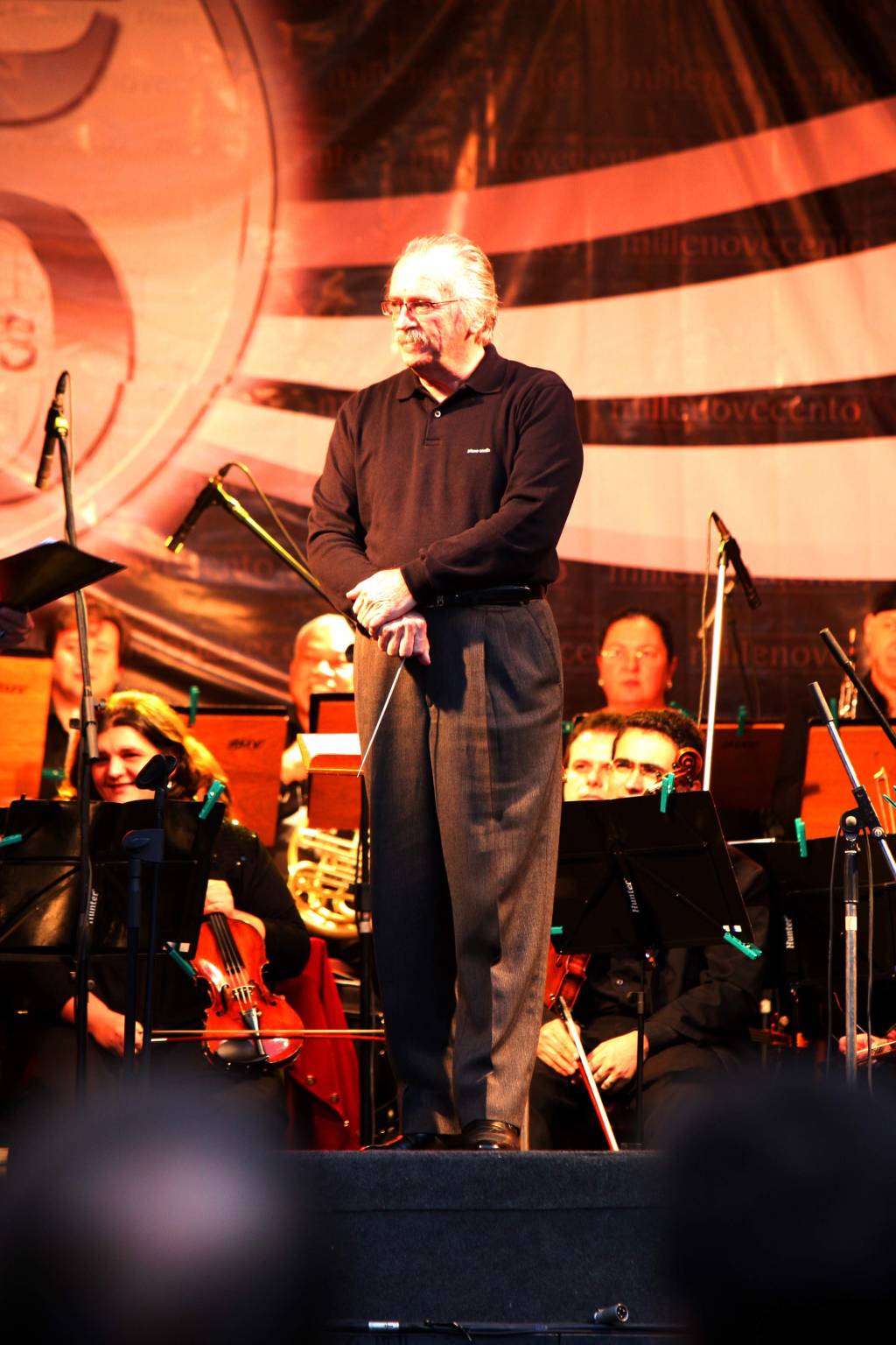 Imagem mostra homem grisalho de roupa preta em pé, em palco.