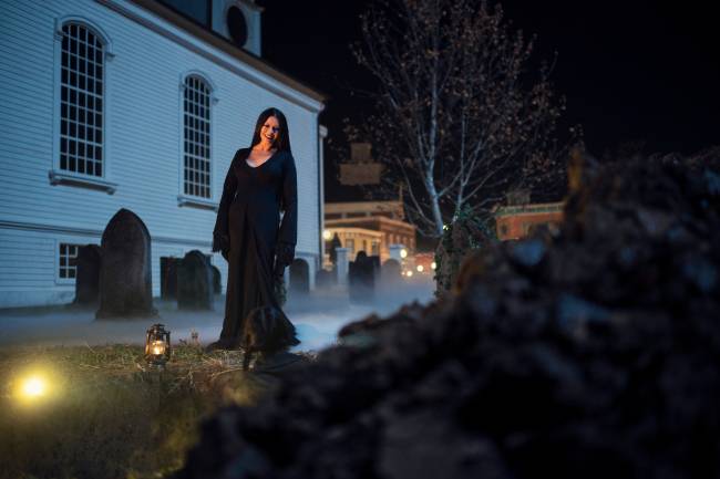 Catherine Zeta-Jones como Morticia Addams na frente de um túmulo
