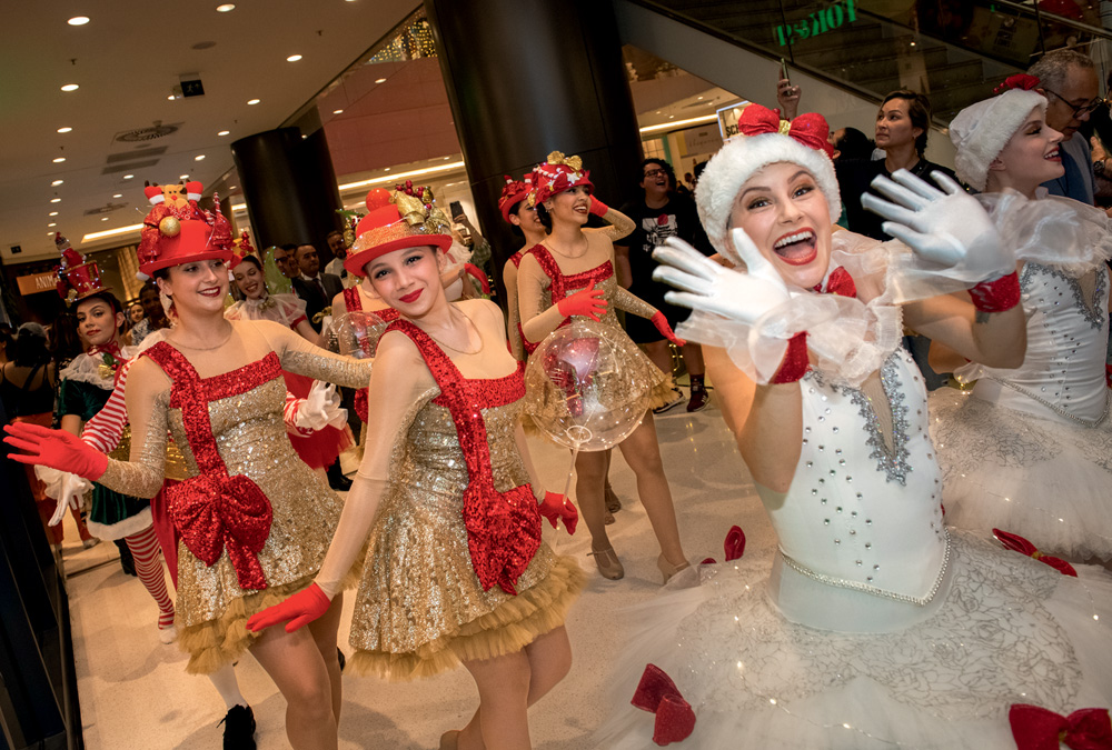 Dançarinos e artistas vestidos com roupas natalinas em fila