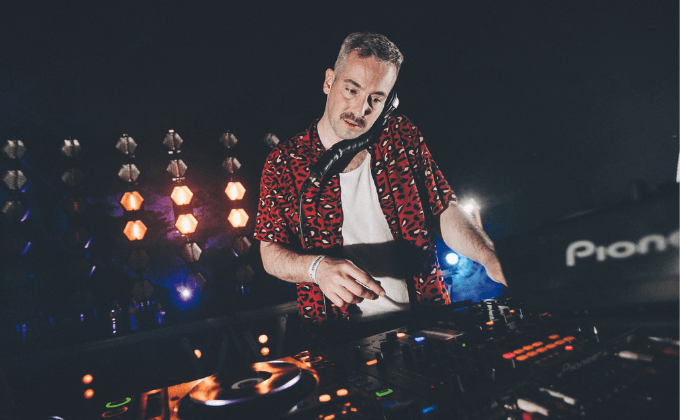 Design sem nome (4) Imagem mostra DJ de camisa estampada tocando em palco