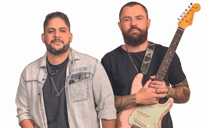 Imagem mostra dois homens de barba. O da direita segura uma guitarra rosa