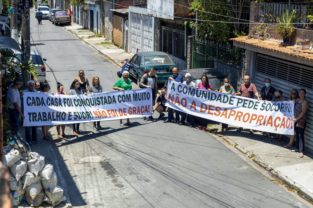 Foto de moradores segurando cartaz escrito "Não à desapropriação" no meio da rua no Jardim Vilas Boas