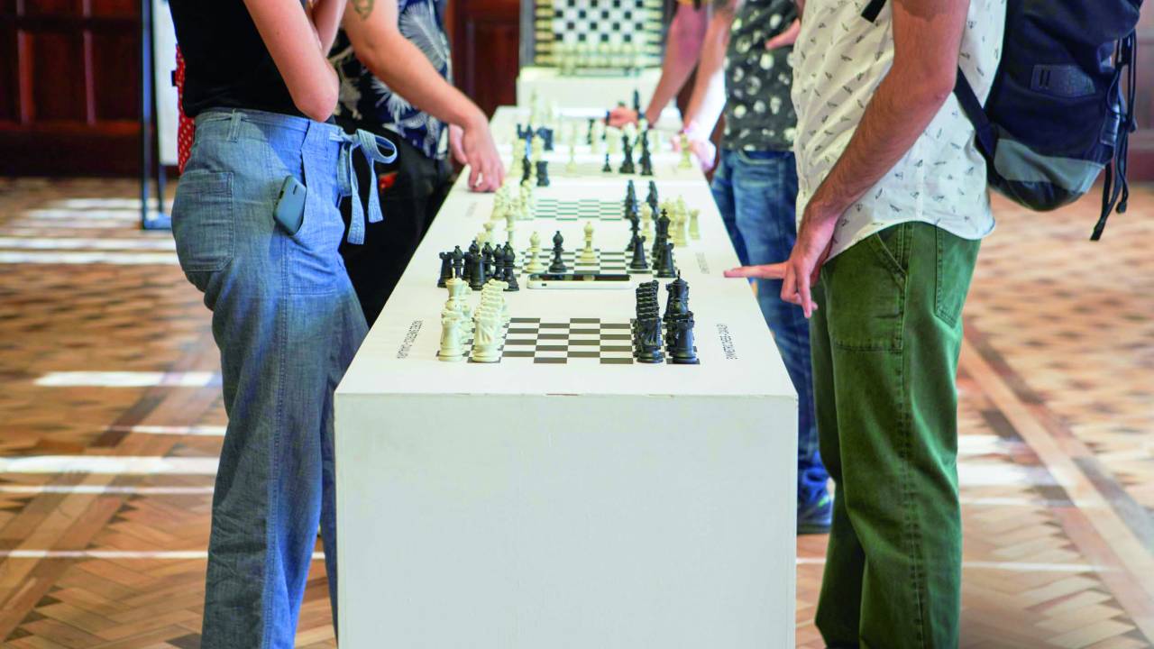 Imagem mostra tabuleiros de xadrez enfileirados com pessoas jogando