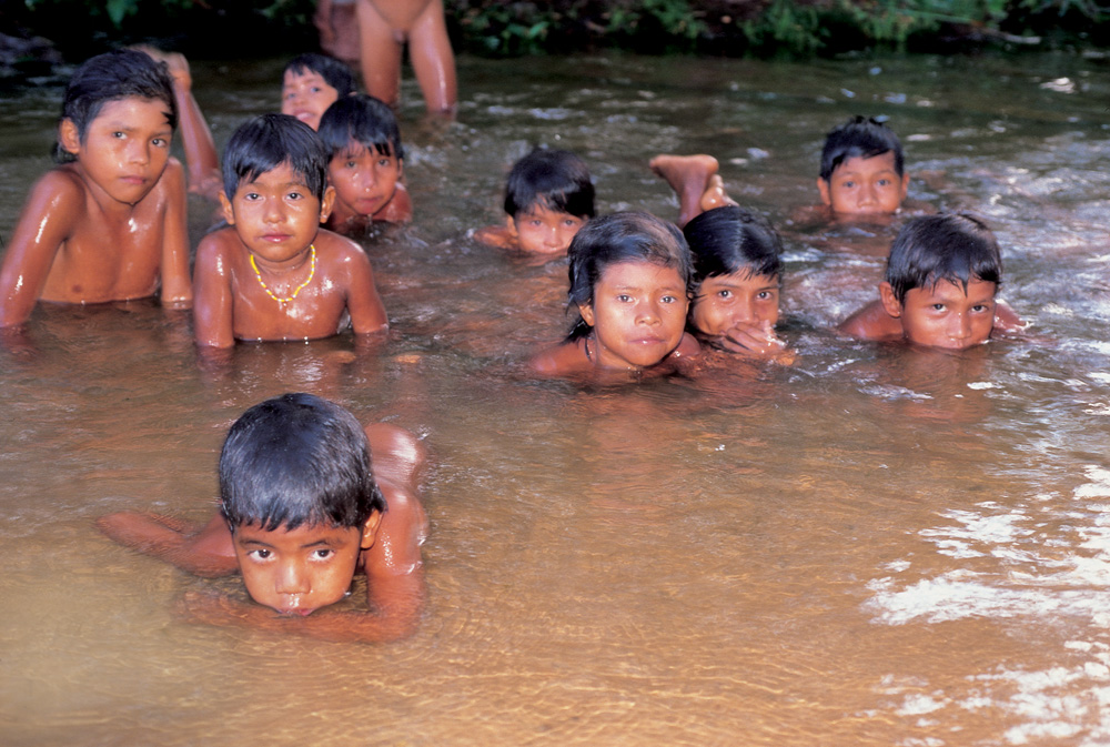 Imagem mostra diversas crianças da etnia indígena xerente nadando em rio