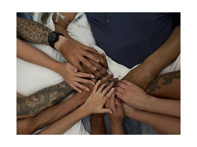 Foto mostra dez mãos se unindo, segurando uma só, a de Pelé