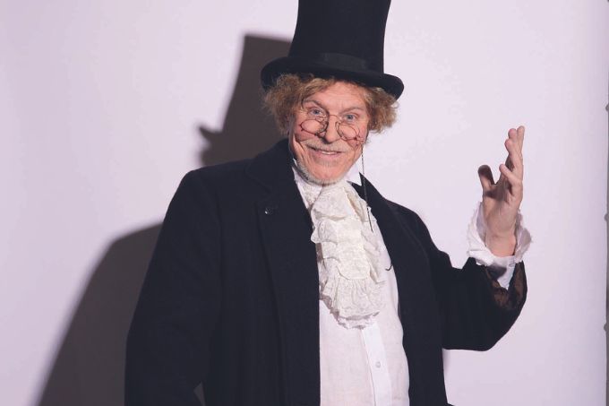 Miguel Falabella como a Ebenezer Scrooge, personagem de "A Christmas Carol", um idoso branco com cabelos grisalhos e roupa luxuosa do século XIX