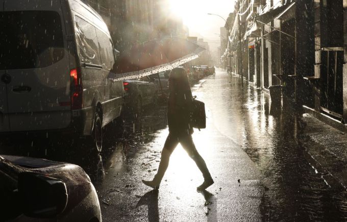 Imagem de pessoa atravessando rua no meio da chuva.
