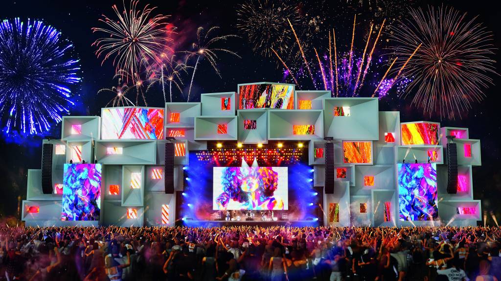 Imagem mostra representação 3D de palco de festival com fogos de artifício ao fundo