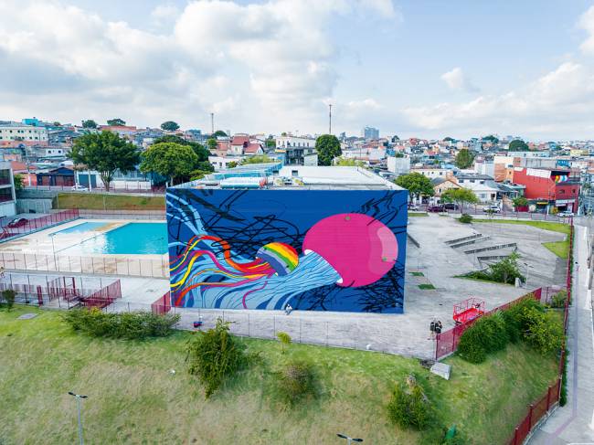 Flip&Bento – Crédito Chu Juke.jpg Foto mostra grafite em uma empena com uma criatura rosa com tentáculos azuis e uma criatura semelhante menor, colorida