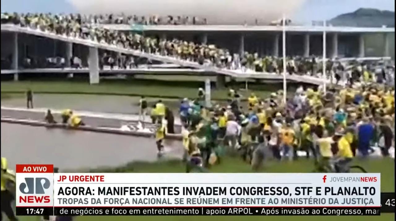 Captura de tela da Jovem Pan, com vídeo dos manifestantes invadindo o Congresso e abaixo GC que informa que manifestantes invadiram o Congresso
