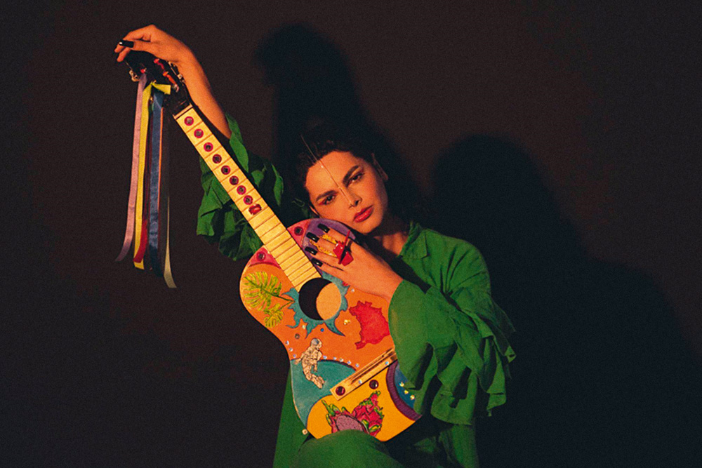 Imagem mostra pessoa abraçada com violão colorido