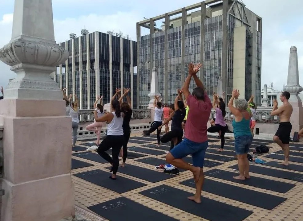 pessoas com os braços erguidos praticante ioga no terraço do prédio