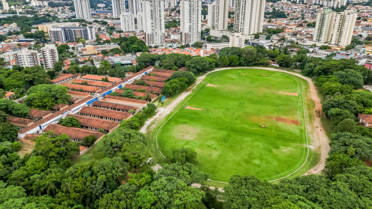 Foto aérea da Chácara do Jockey, grande gramado, com prédios ao fundo