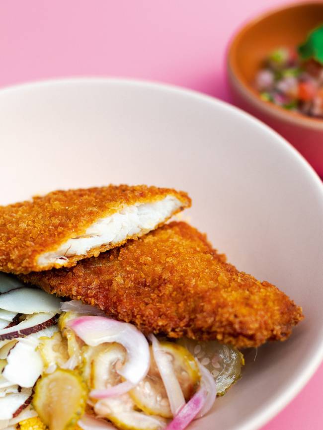 cuscuz da irina peixe imagem de um peixe frito cortado ao meio em cima do cuscuz e ao lado de cebola e maxixe cortados