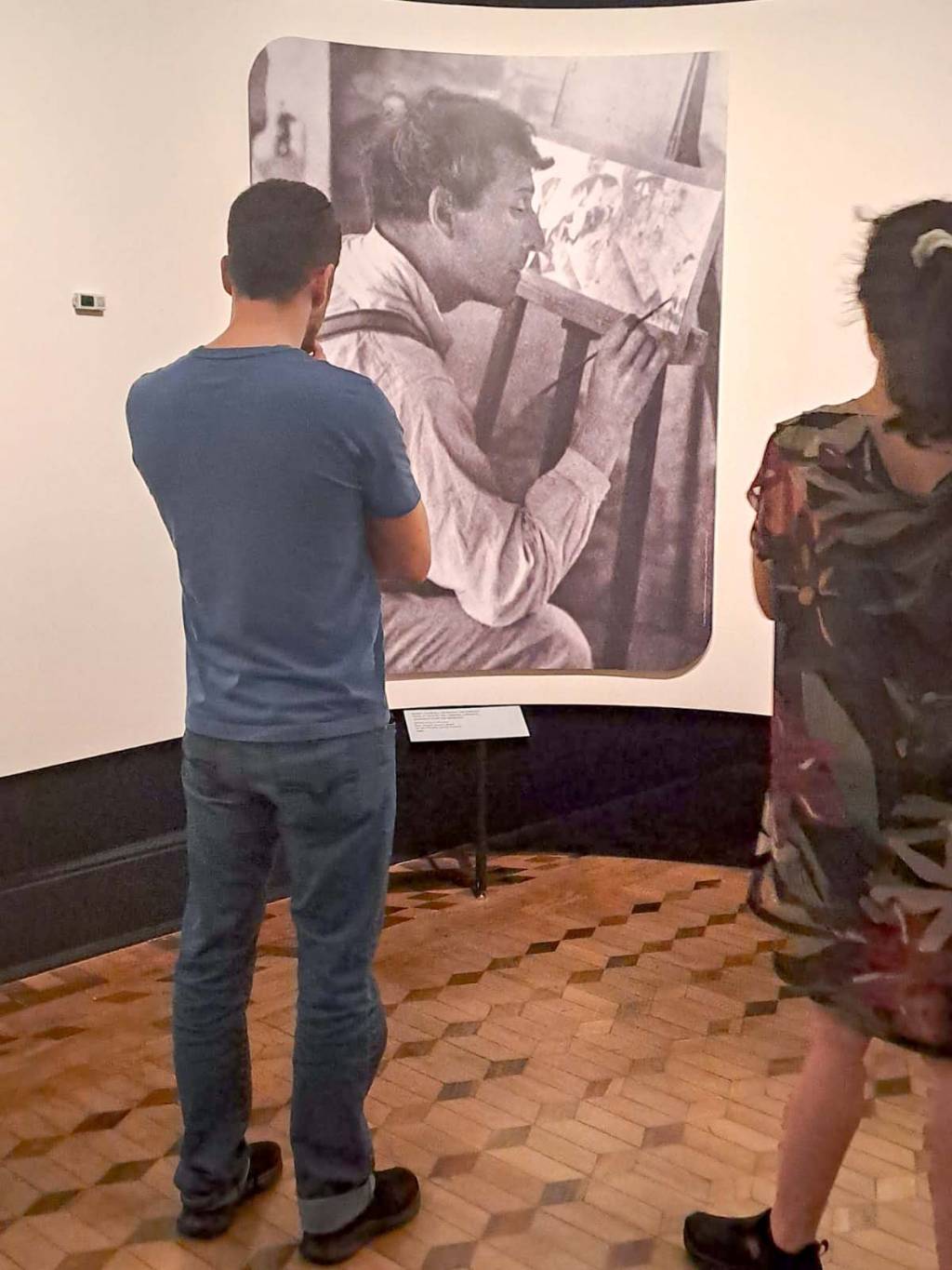 Um homem e uma mulher olham para uma foto em preto e branco de Marc Chagall pintando. Eles estão de costas