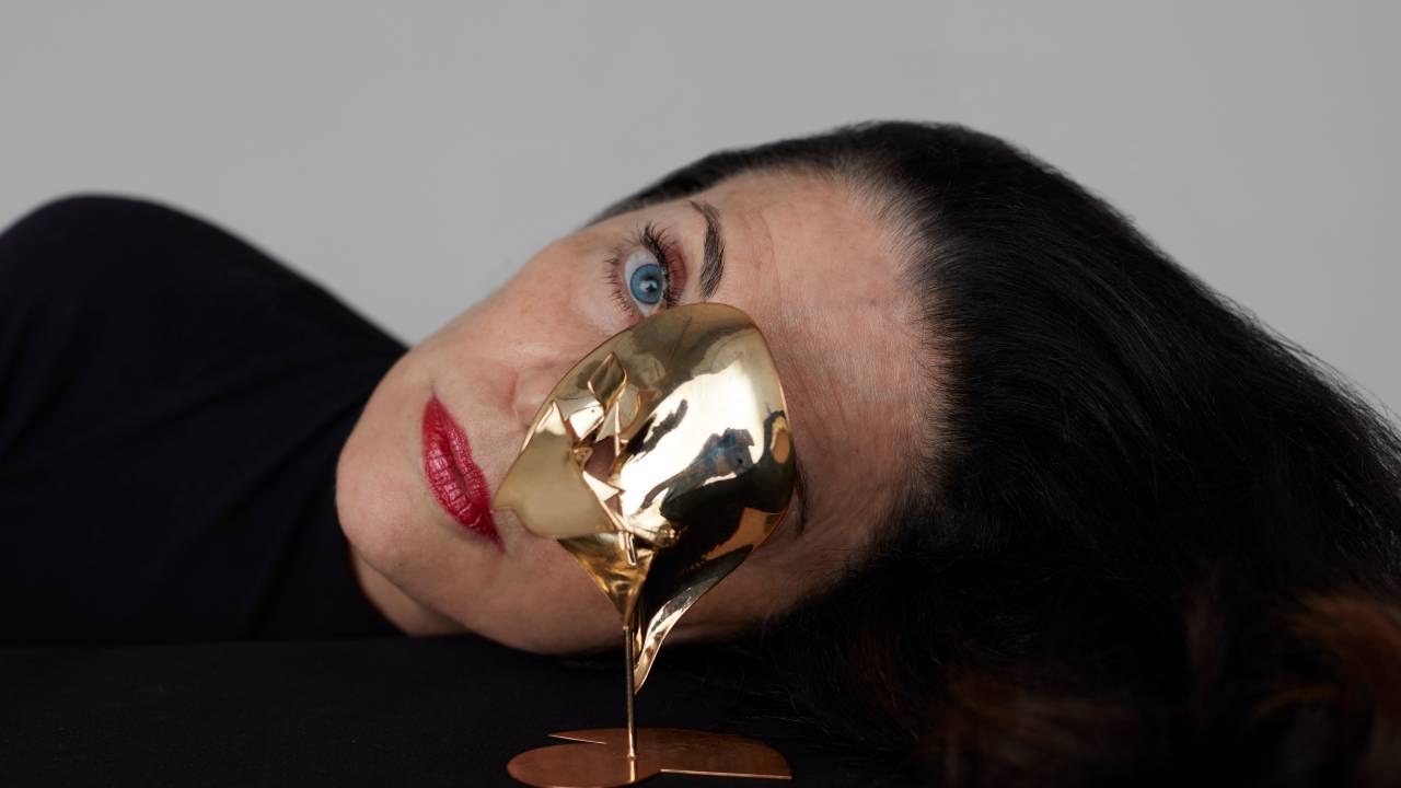 Rosto de uma mulher com uma escultura dourada na frente