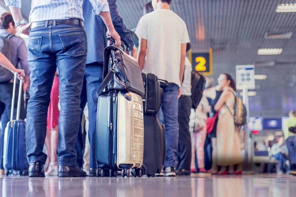 Imagem mostra saguão de aeroporto com diversas pessoas