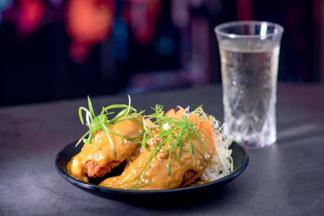 Katsu baga kare (polpettone com kare) – Izakaya – The Oriental Izakaya prato de cerâmico com dois bolinhos cobertos com curry e cebolinha e arroz