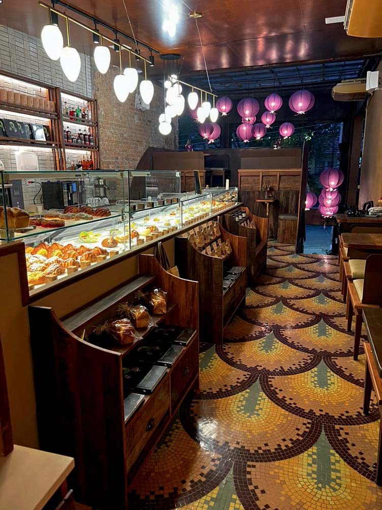 Ambiente interno com chão de mosaico de ladrilhos, balões cor-de-rosa e balcões com produtos