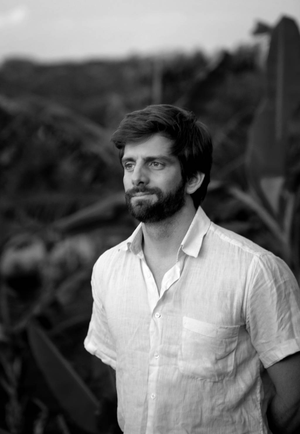 Foto em preto e branco exibe homem com barba vestindo camisa branca.