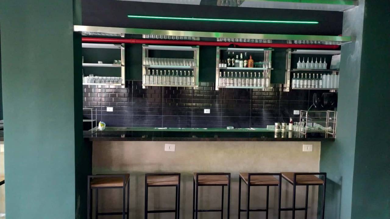 Fachada de bar com balcão escuro e banquetas